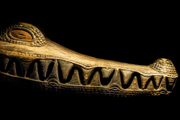 A close-up of a meticulously carved wooden crocodile face, showcasing detailed craftsmanship...