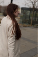 Fototapeta premium A woman dressed in a stylish white coat is standing on a bustling sidewalk, exuding elegance and fashion