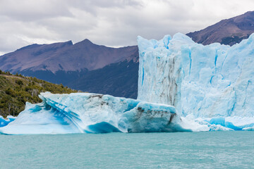 Patagonia famous glacier Perito Moreno in Argentina. Blue ice blocks falling in the lake at the bottom of huge patagonian glacier, part of the Patagonia ice fields. Lake full of icebergs
