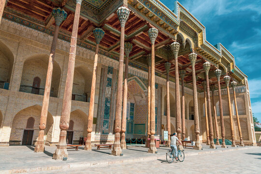 A man rides a bicycle in front of a building with pillars