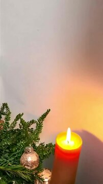 A beautifully arranged Christmas centerpiece featuring a mix of greenery, pinecones, and ornaments in soft rose gold tones. The scene is enhanced with warm candlelight, creating a cozy and festive hol