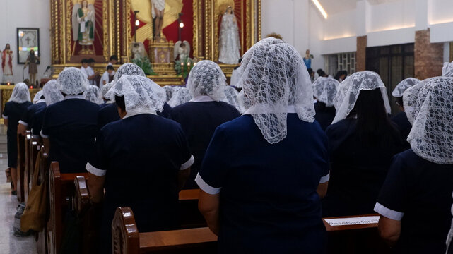 Members of the Catholic Women's League (CWL) in blue uniforms are attending a holy Mass before an oath-taking ceremony.