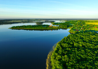 Lake aerial view. Green Forest at lake in rural, drone view. Island on the lake, bird's eye view. Ruins of Trinity Church in Belaya Tserkov Village, Chashniki District, Vitebsk Region in Belarus.