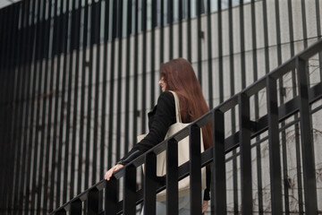 A woman is gracefully walking down a set of stairs, which are elegantly designed and...