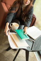 Obraz premium A woman is sitting comfortably at a table covered with various papers and a steaming cup of coffee, engaged in her work or studies