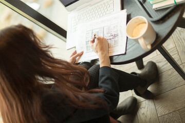 A woman is sitting quietly at a table, focused on writing diligently on a piece of paper, deeply...