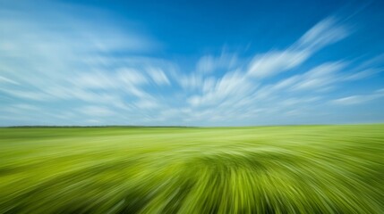Obraz premium Dynamic landscape view of a vibrant green field under a vivid blue sky.