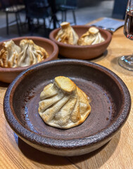 Close-up of Fried Khinkali, Traditional Georgian Dumplings, in Rustic Ceramic Bowls.Appetizing Georgian Cuisine: Baked Khinkali Served in Earthenware on Wooden Table