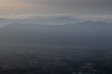 Fototapeta premium Aerial view of village of yelagiri from the mountain top, a top view, mountains covered with mist. Yelagiri hill station, nearest to Chennai