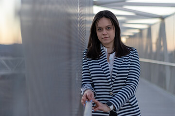 Obraz premium Young businesswoman standing on a modern bridge at sunset