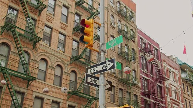 Traffic signal, one way street signs marking Mott Street intersection in historic Manhattan neighborhood during sunny urban daylight. NYC, USA, 11.5.2024