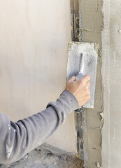 Craftsman uses a float trowel and cement to plaster a house wall. Construction process