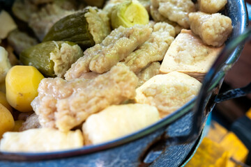 A colorful mix of Siomay, including steamed dumplings, stuffed peppers, potatoes, and tofu, arranged in a blue pot. Popular Indonesian street food.