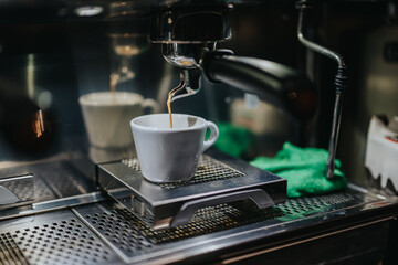 Espresso is dispensed into a cup from an advanced coffee machine in a lively cafe ambiance, showcasing the elegance of preparing fine coffee beverages.