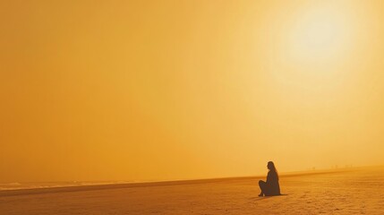 Silhouette of person on golden beach at sunset.