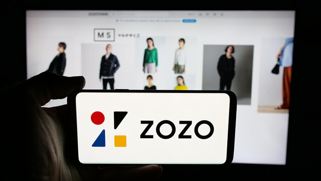 Stuttgart, Germany - 04-25-2025: Person holding cellphone with logo of Japanese e-commerce company ZOZO Inc. on screen in front of webpage. Focus on phone display.