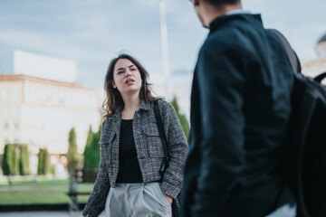 Two business people engage in a focused conversation outdoors, emphasizing teamwork and...