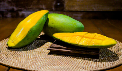 Fresh ripe mango sliced in half, revealing juicy golden flesh. Perfect for tropical fruit, healthy food, summer, and natural snack themes. On dark wooden background.