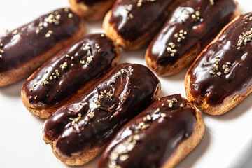 Eight classic eclairs arranged neatly on a white plate.