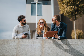 Group of three people engaging in conversation and brainstorming while standing outside. They...