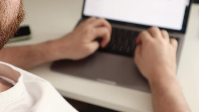 Student typing a term paper on a laptop keyboard while sitting at a desk in his dorm room