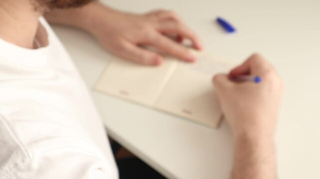 The man demonstrates the finished work by putting his pen in a notebook on the table