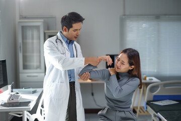 Obraz premium Asian doctor checking arm and shoulder of young woman experiencing pain during medical examination in hospital room