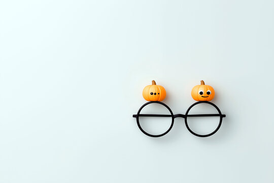 Cute black glasses decorated with small pumpkins and googly eyes on light background