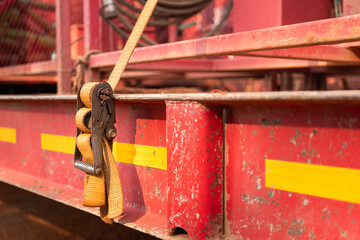 Latching belt strap with metal buckle that securing heavy load on trailer truck to prevent object...
