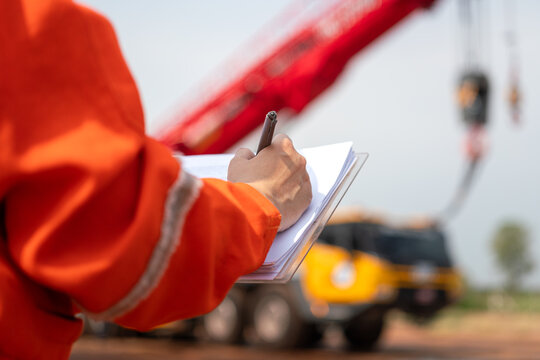 An engineer or foreman is checking on safety checklist form of lifting crane at the drilling rig work site. Industrial safe working concent, close-up and selective focus.
