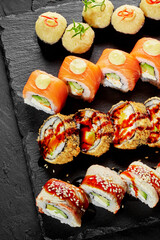 Delicious sushi rolls with salmon, avocado, and cream cheese filling on black slate plate