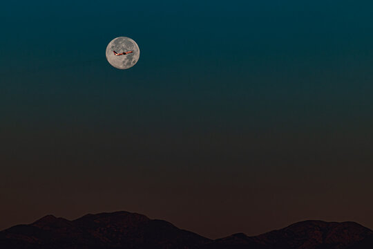 Aeroplane flying across a full moon