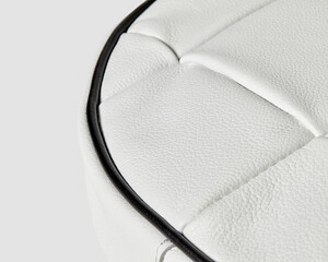 White leather upholstery detail showing stitching and piping