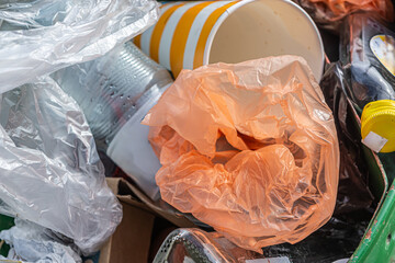 Piles of various plastic waste in a trash can, including beverage bottles, aluminum cans, and other plastic containers.