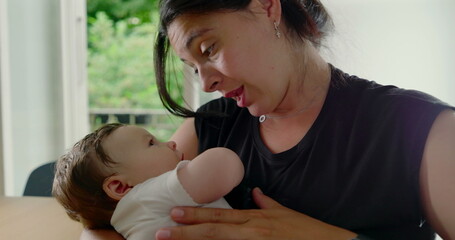 Mother and baby enjoying a loving moment, with the baby comfortably nestled in her arms,...