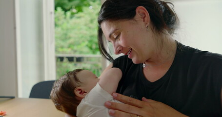 Mother and baby enjoying a loving moment, with the baby comfortably nestled in her arms, highlighting the bond and affection between them in a warm, cozy home environment-SD 480p