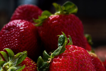 Fresh red strawberries showing seeds and green leaves