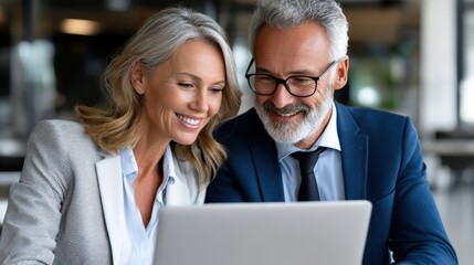 Obraz premium A man and woman are looking at a laptop together