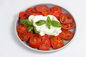 A ball of burrata surrounded by sliced tomatoes, seasoned with olive oil and fresh basil