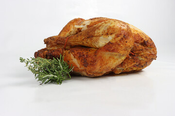 A whole roasted chicken placed on a white background, showcasing a golden-brown, crispy skin with herbs and seasonings © eds30129