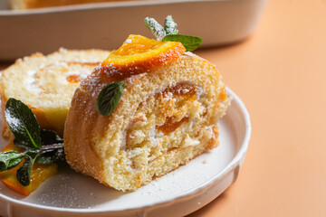 Orange sponge roll with cream and mint in a white plate on a bright background