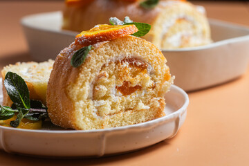 Orange sponge roll with cream and mint in a white plate on a bright background