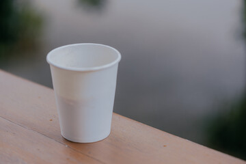 Craft paper glass on wooden table with blur background, copy space for text.