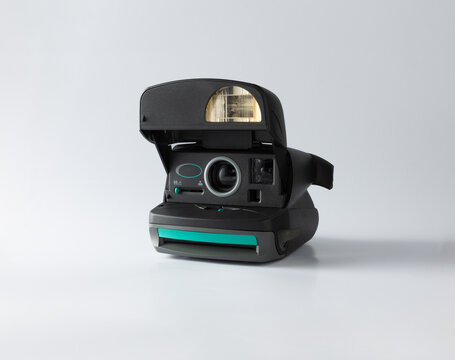 A retro Polaroid instant camera with pop-up flash on a white background. This close-up highlights the timeless design and nostalgic charm of analog photography equipment.