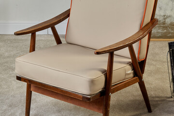 Comfortable vintage armchair with wooden frame and beige cushions