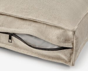 Close-up of zipper on beige fabric cushion cover showing inner filling