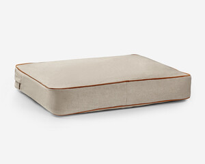 Empty rectangular beige pet bed with brown leather piping on white background