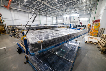 Crane lifting stack of solar panels in warehouse