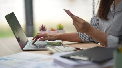 young asian woman employee clerk shopping online paying bill with credit card using smartphone. Sitting in a modern office at a workplace at computer desk. cute female worker uses mobile phone. Asia - Powered by Adobe