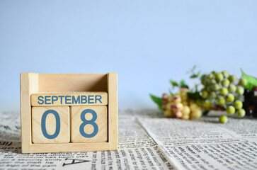 September 8, Calendar cover design with number cube with fruit on newspaper fabric and blue background.	